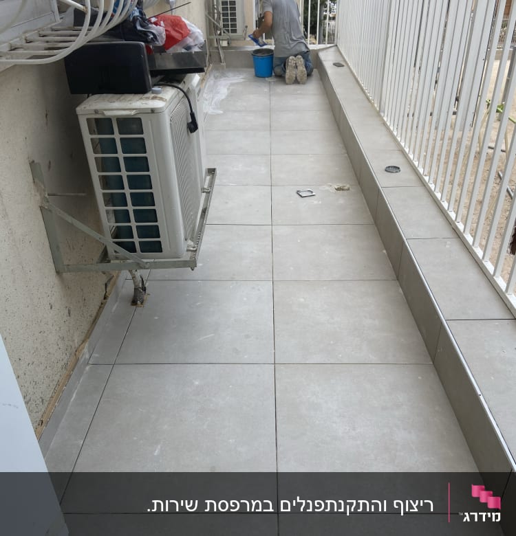 אדם עובד על רצפת מרפסת עם דלי כחול